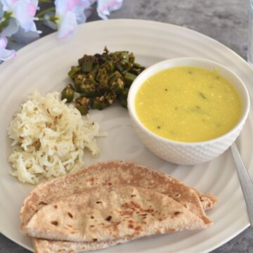 Lunch thali served which has khapli wheat roti, jeera rice, bhindi and takhachi kadhi.
