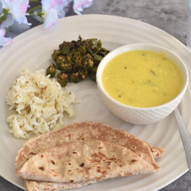 Lunch thali served which has khapli wheat roti, jeera rice, bhindi and takhachi kadhi.