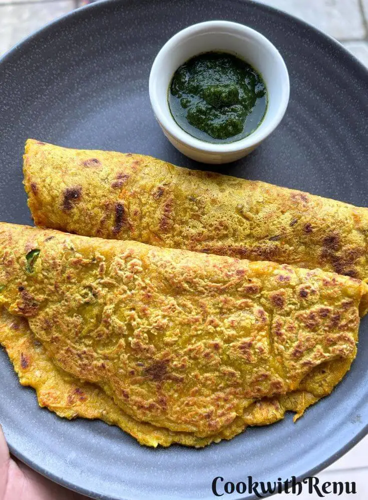 Oats Vegetable pancake served in a blue plate with some chutney on side.
