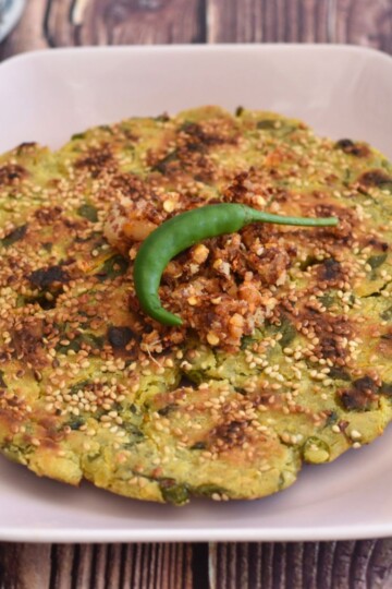 Beet Greens, Carrot, Jowar Thalipeeth served in a pink hexagon plate.