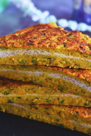 Cut Slices of Moong Dal toast layered on a black cheese board.