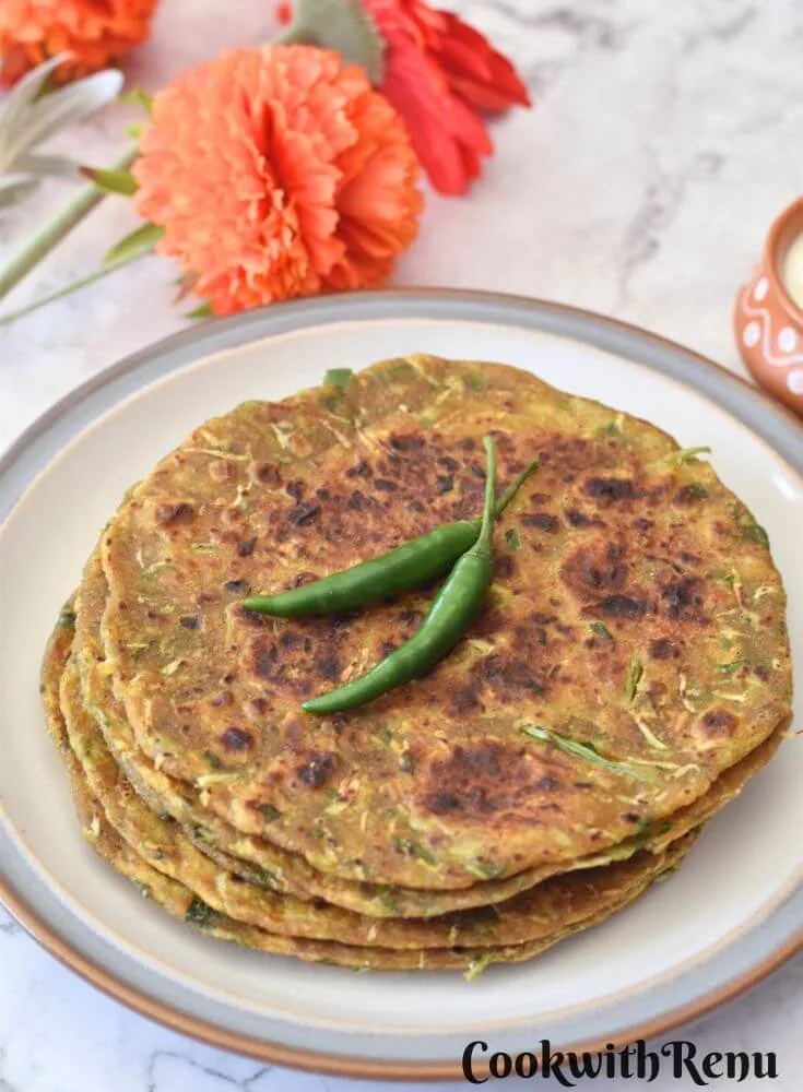 3-4 Dudhi Paratha served in a white plate with some green chilies on top and some yogurt in a bowl.