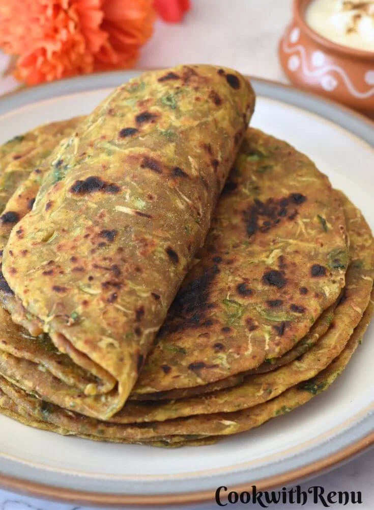 5-6 Dudhi Paratha served in a white plate, of which 2 are rolled.