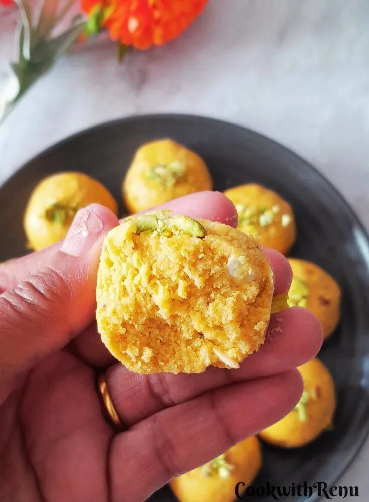 Close up texture of Half Besan Ladoo. Seen in the background are some more besan ladoo arranged in a black plate.