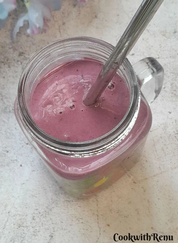 Banana Berry Protein Smoothie served in a glass with a steel straw in it.