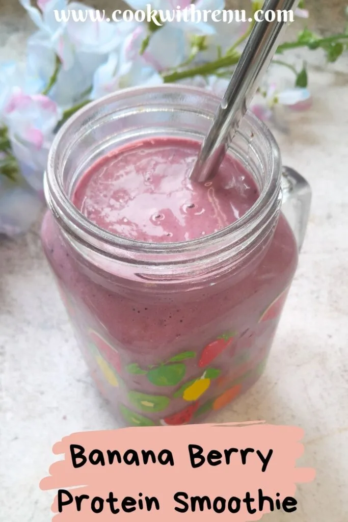 Banana Berry Protein Smoothie served in a glass with a steel straw in it. Seen in the background are some flowers.
