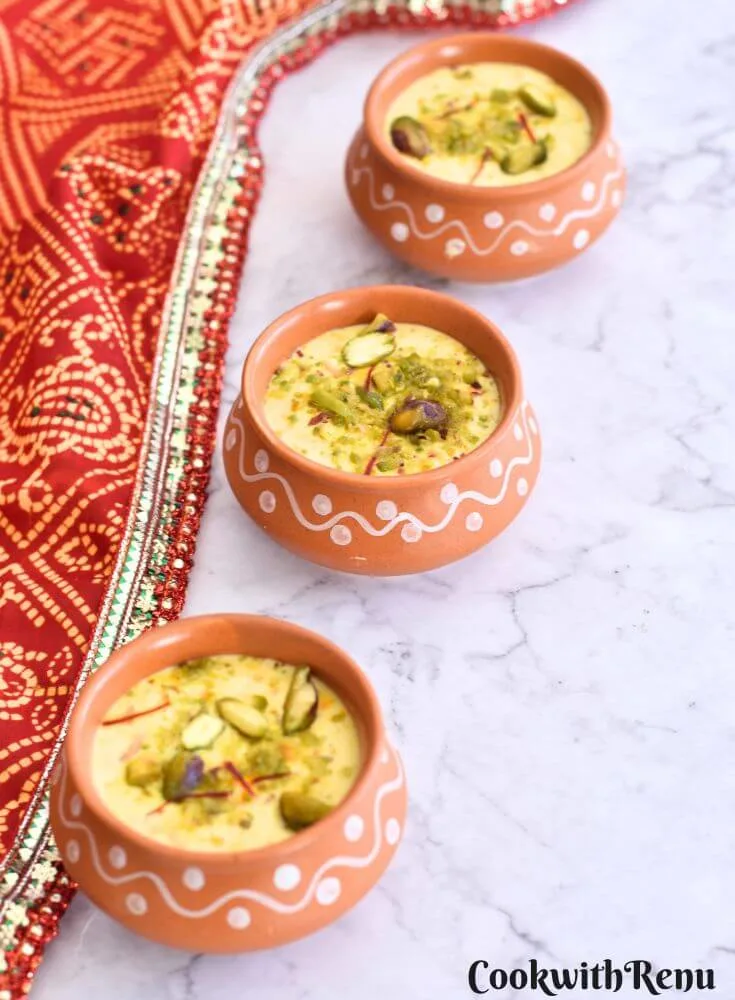 Top view of Kesar Pista Shrikhand served in 3 different brown bowls with a garnish of pista and saffron.