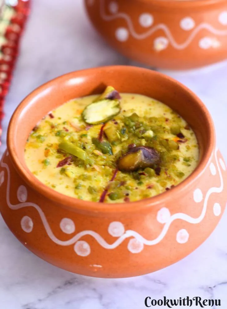 Close up view of Kesar Pista Shrikhand served in at brown bowl with a garnish of pista and saffron.