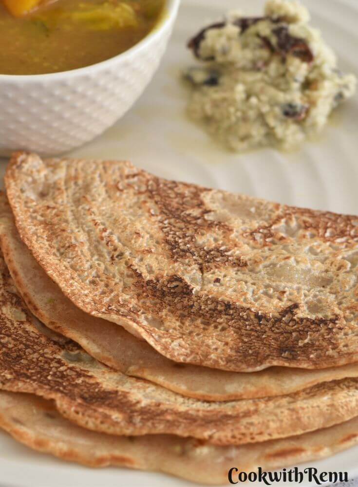 Close up look of Khapli Wheat Dosa served in a cream plate along with chutney and sambar.