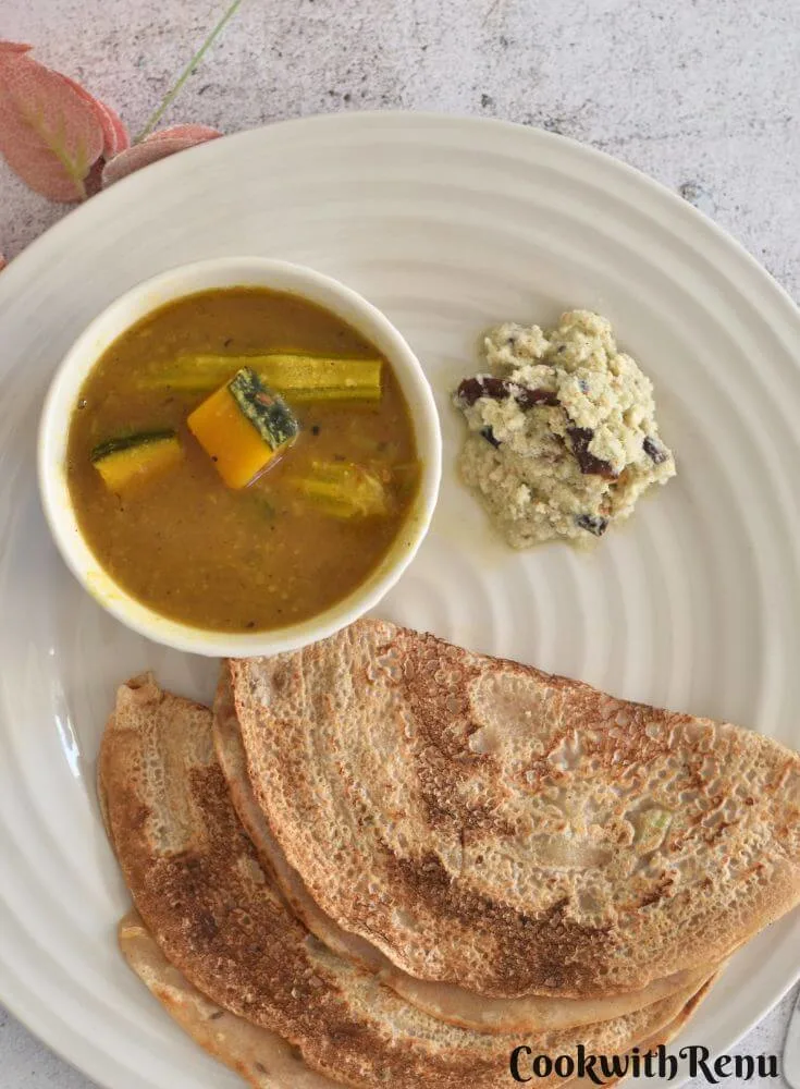 Top view of Khapli Wheat Dosa served in a cream plate along with chutney and sambar.