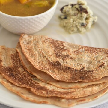 Khapli Wheat Dosa served in a cream plate along with chutney and sambar.
