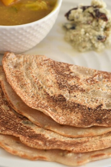 Khapli Wheat Dosa served in a cream plate along with chutney and sambar.