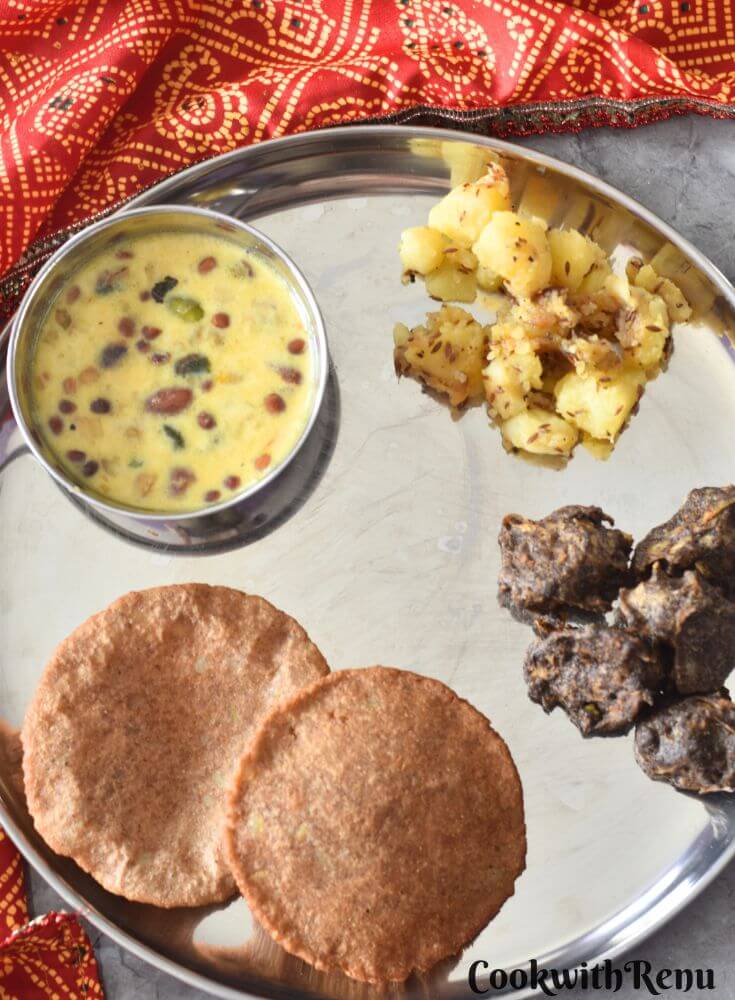 Thali featuring, Upaas ki thali with makhana kheer, aloo kali mirch, crispy kuttu pakoda, and puri, in clockwise directrion starting from top. A glass of water is on the side.