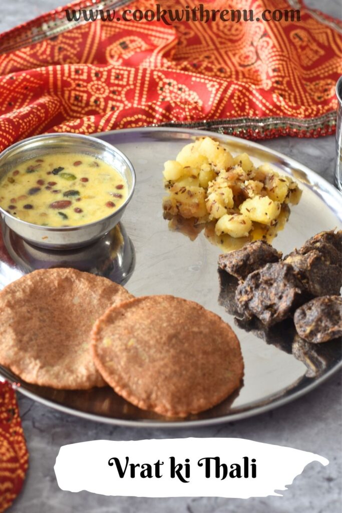 Thali featuring, Upaas ki thali with makhana kheer, aloo kali mirch, crispy kuttu pakoda, and puri, in clockwise directrion starting from top. A glass of water is on the side.