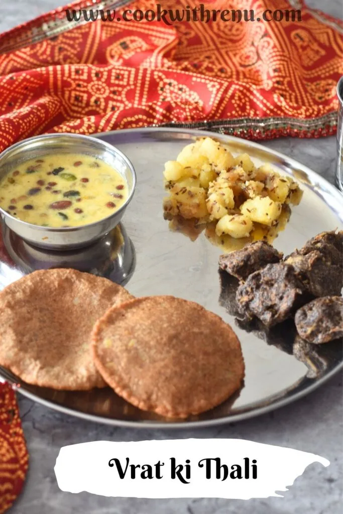 Thali featuring, Upaas ki thali with makhana kheer, aloo kali mirch, crispy kuttu pakoda, and puri, in clockwise directrion starting from top. A glass of water is on the side.