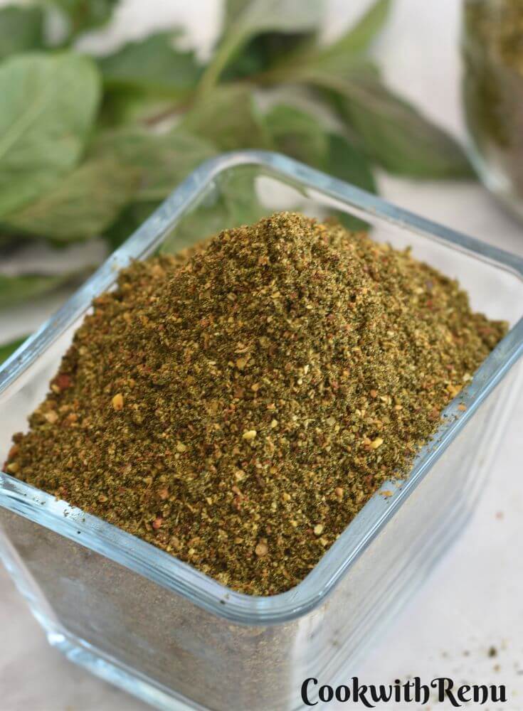 Mint Podi in a rectangular glass bowl. Seen in the background is some mint leaves.