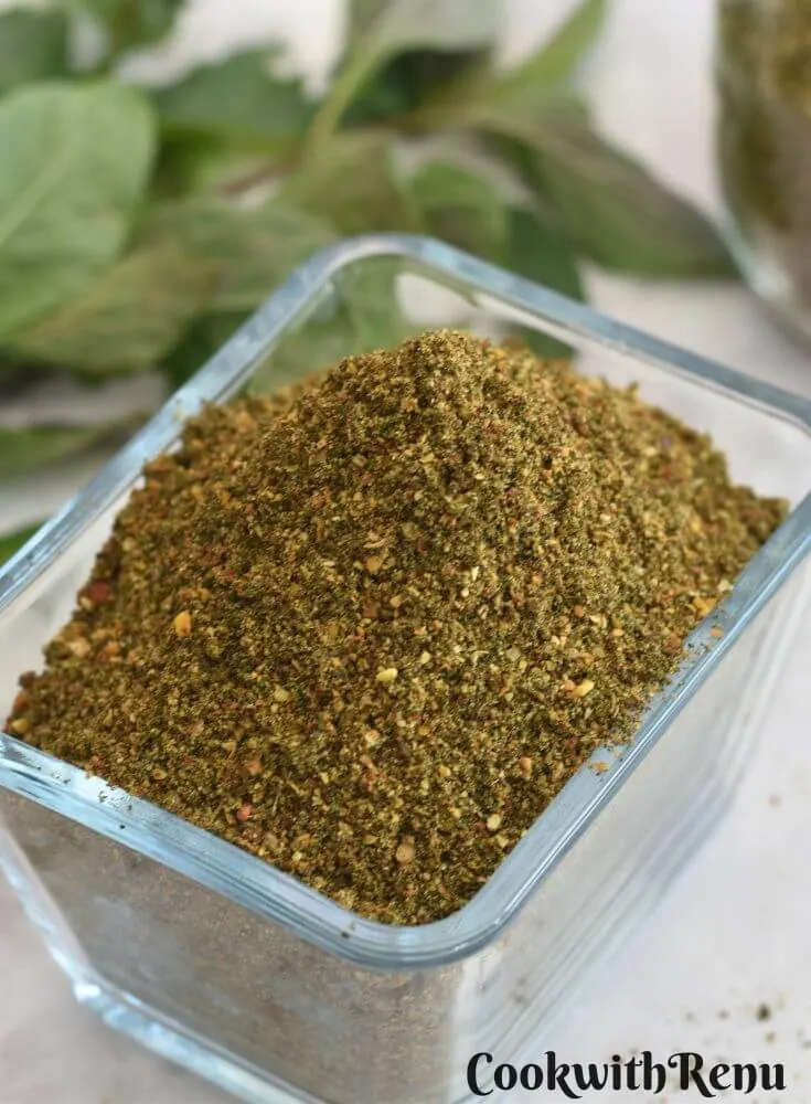 Mint Podi in a rectangular glass bowl. Seen in the background is some mint leaves.