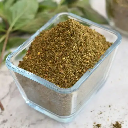 Mint Podi in a rectangular glass bowl. Seen in the background is some mint leaves.