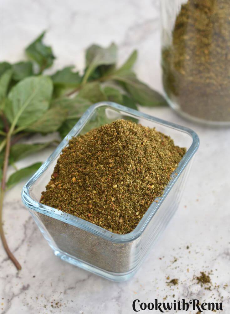 Mint Podi in a rectangular glass bowl. Seen in the background is some mint leaves and jar filled with mint podi.