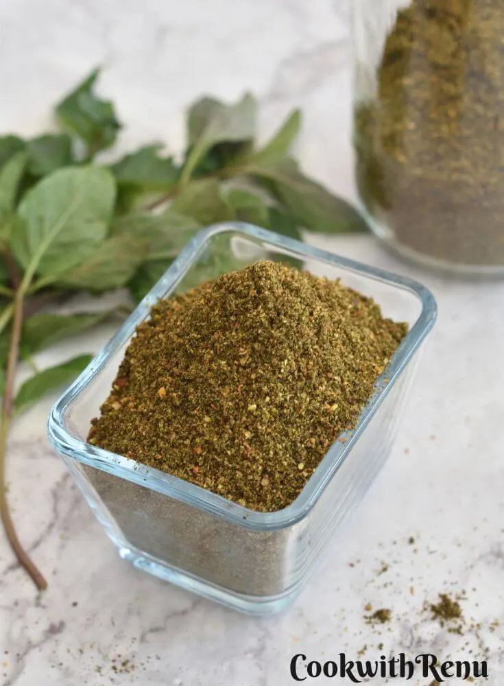 Mint Podi in a rectangular glass bowl. Seen in the background is some mint leaves and jar filled with mint podi.