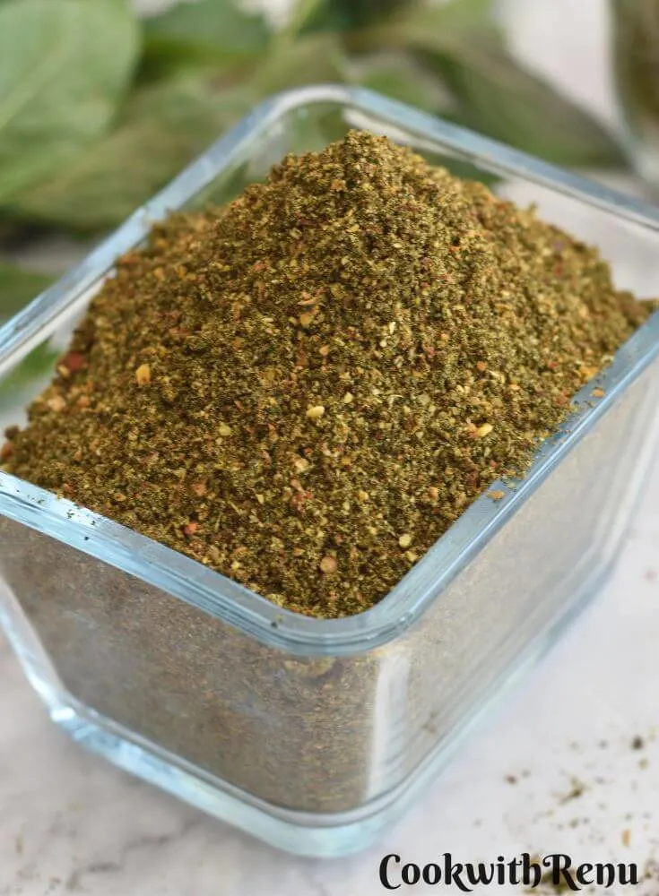 Mint Podi in a rectangular glass bowl. Seen in the background is some mint leaves.