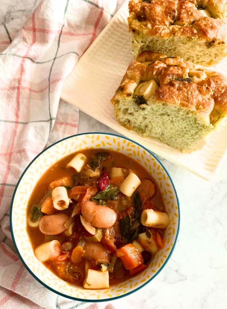 Minestrone Soup served in a bowl, seen in the background, is some chutney-spiced focaccia.