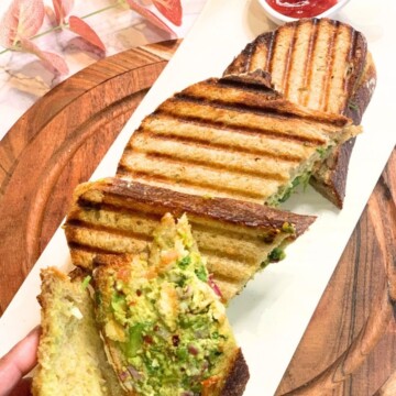 A Veg sandwich is seen in a slice, along with a few more sandwich slices seen in the white plate.