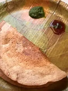 Mix Dal Beetroot Chila served in an eco-friendly plate along with green coriander and tamarind chutney.