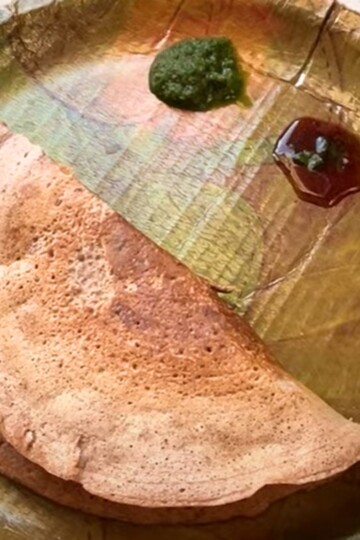 Mix Dal Beetroot Chila served in an eco-friendly plate along with green coriander and tamarind chutney.