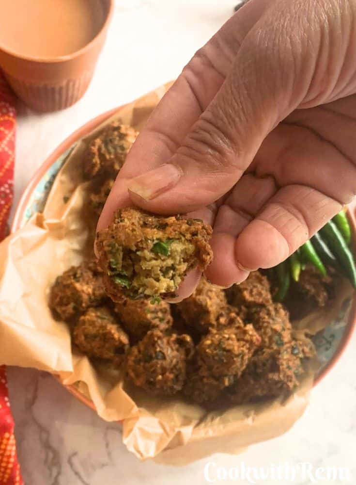 Image showing a bowl filled with paush vada with green chillies on the side along with chutney and tea.