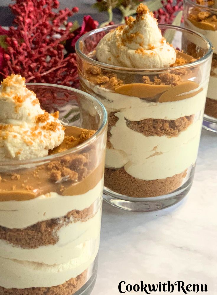 Close-up look of Biscoff Dessert Cups served in small glasses, with artificial flowers in the background.
