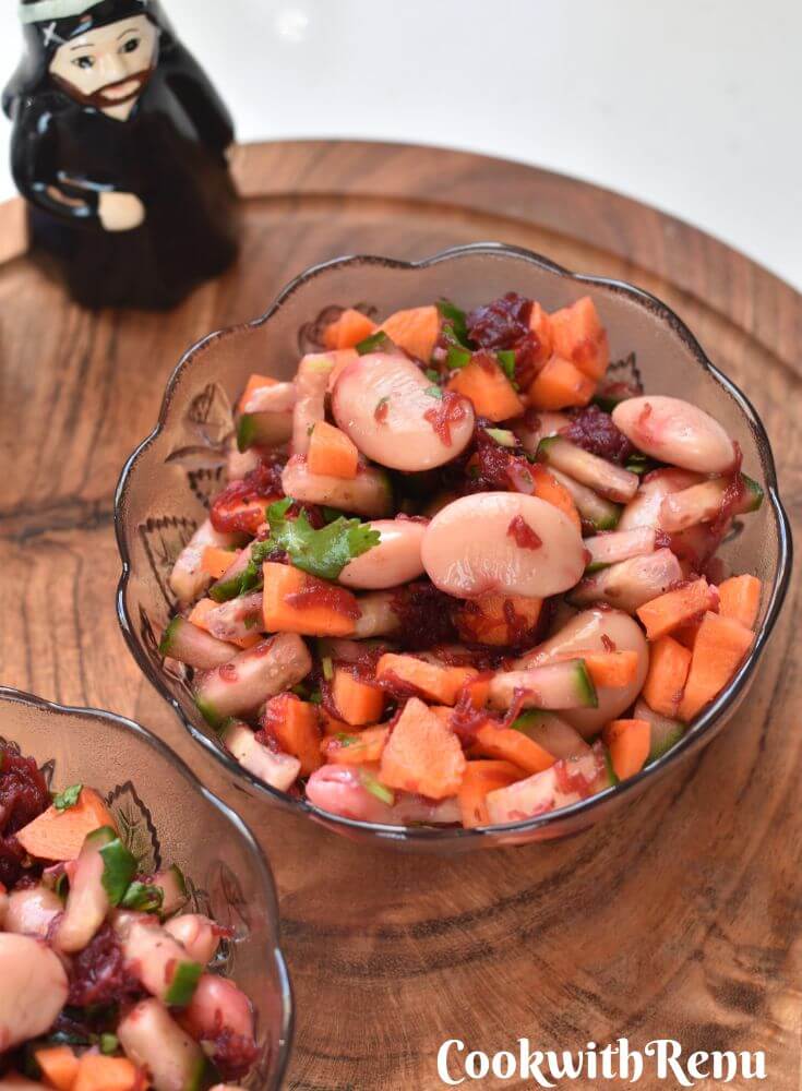 Butter Beans Salad served in 2 glass bowls and kept on a brown cheese board. Seen in the background are salt and pepper shakers.