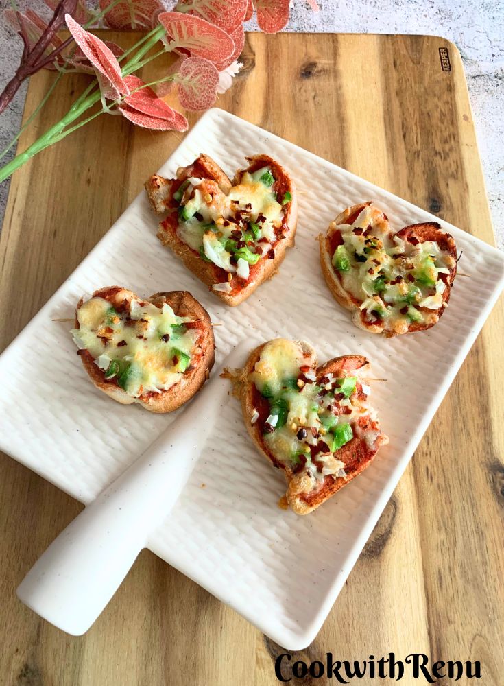 Heart-Shaped Pizza served on a white plate, with artificial flowers in the background.