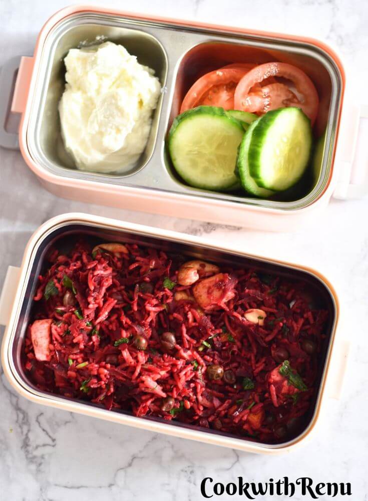 Beetroot Paneer Rice served in a lunchbox along with some cucumber, tomato, and yogurt.