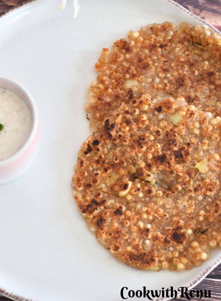 Sabudana Thalipeeth served on a white plate with peanut yogurt raita.