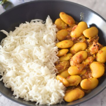 Butter Beans Curry served along with steamed rice, served in a black bowl.