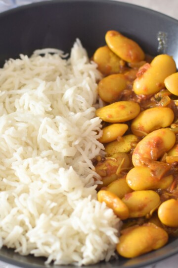 Butter Beans Curry served along with steamed rice, served in a black bowl.