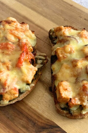 2 slices of Cheese Paneer Tikka Open Sandwich on a cheese board, just baked from air-fryer.