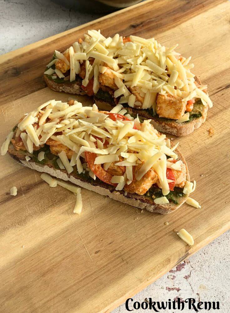 2 Cheese Paneer Tikka Open Sandwich ready to be baked on a cheese board,