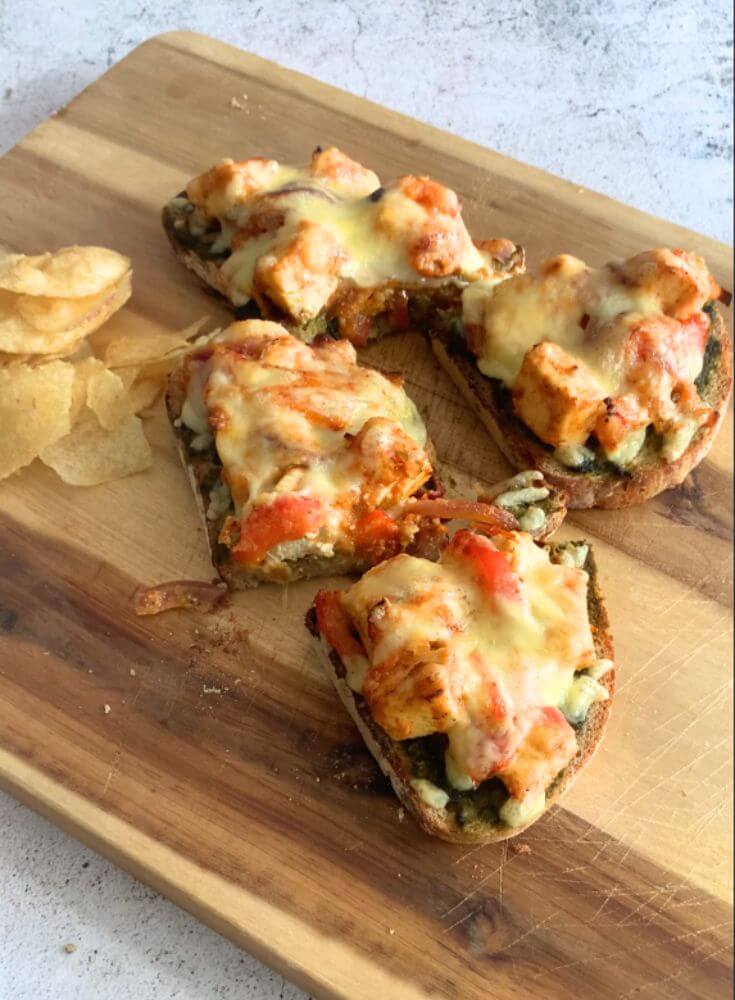 Slices of Cheese Paneer Tikka Open Sandwich served on a cream cheese board along with some crisp.