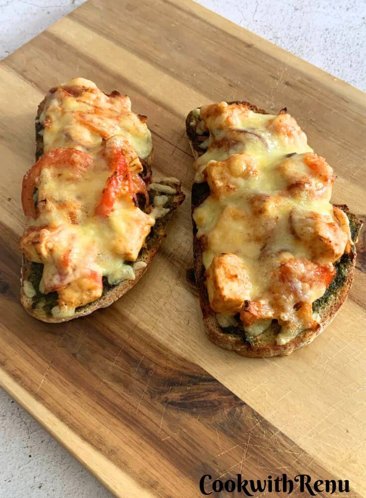 2 slices of Cheese Paneer Tikka Open Sandwich on a cheese board, just baked from air-fryer.