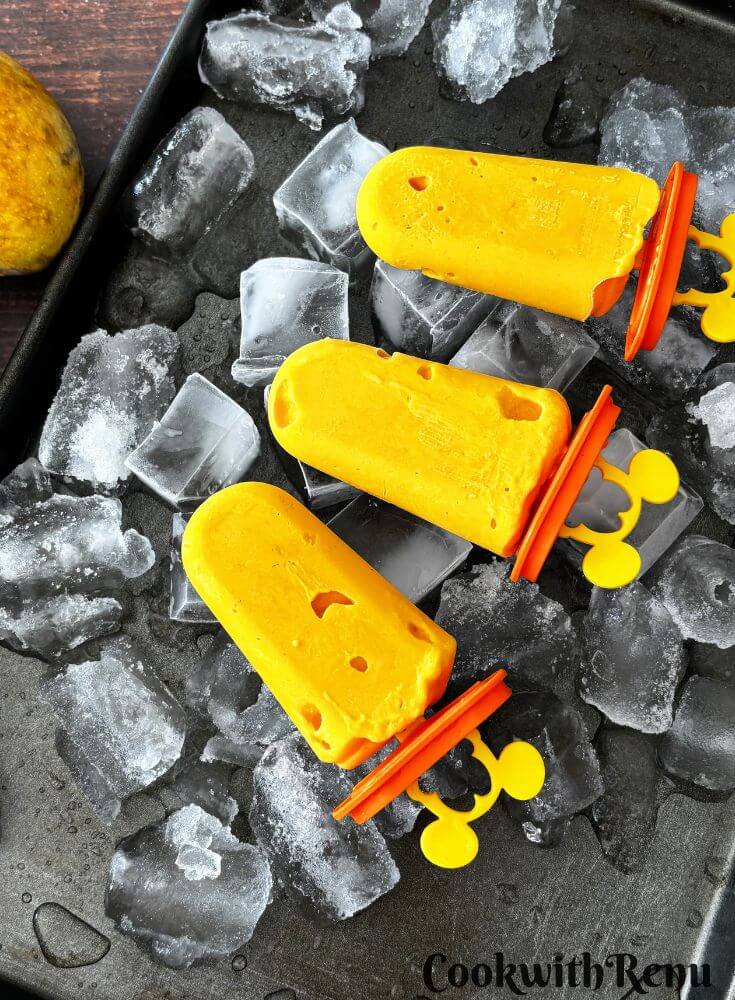 Few popsicles arranged in a tray with ice beneath them.