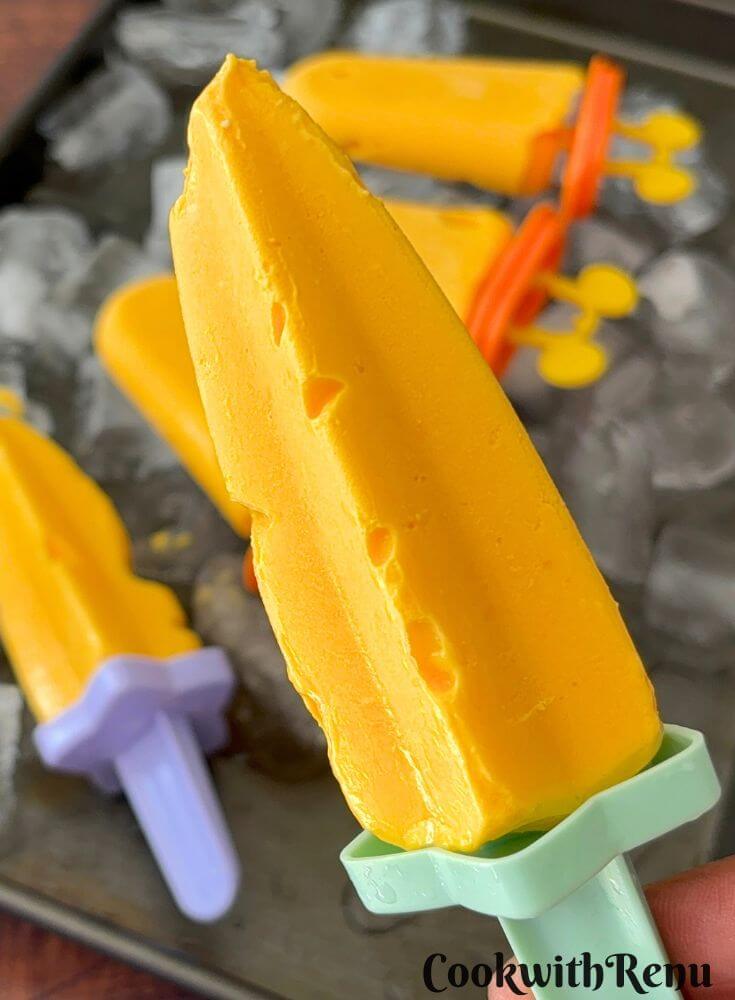 A close-up of a cottage cheese popsicle, with some popsicles on a ice tray in the background.