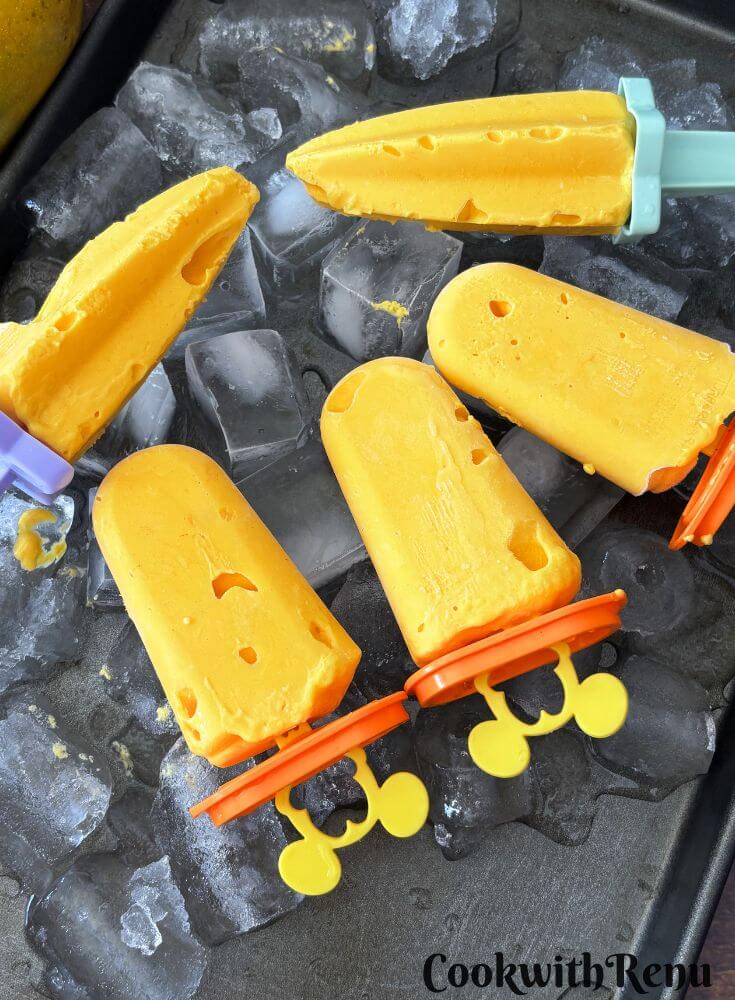 Few popsicles arranged in a tray with ice beneath them.