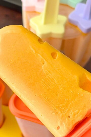 A close-up of a cottage cheese popsicle, with some popsicles in the mold in the background.