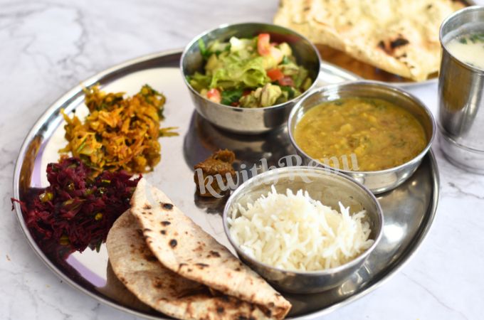 Beetroot Stir Fry served as a part of thali, which has cabbage easy bhaji, salad, moong and arhar dal, steamed rice, roti in a clockwise direction. In the background is chaas and papad.