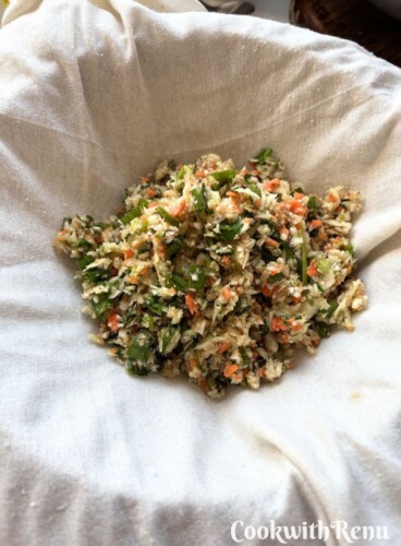 Squeezing out moisture from the veggies in a muslin cloth.