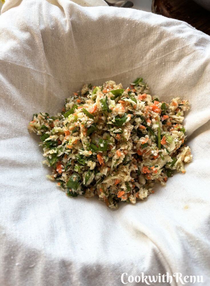 Squeezing out moisture from the veggies in a muslin cloth.