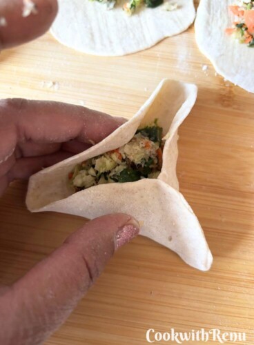 A pic showing shaping the momos into a triangular shape.