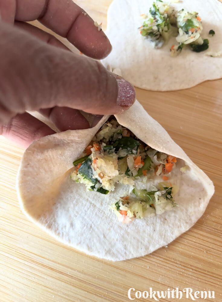 A pic showing shaping the momos into a triangular shape.